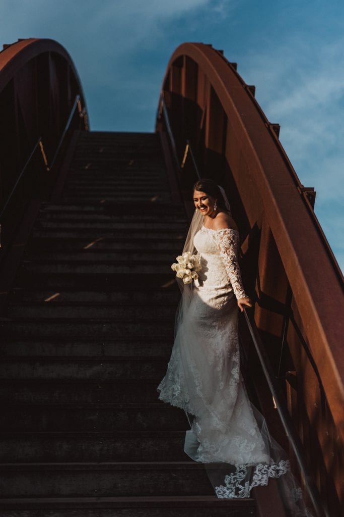 bride laughing while standing on the steps of our rusty rainbow bridge in crescent park new orleans 